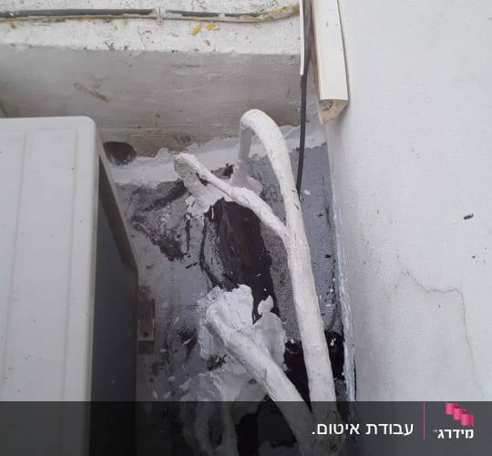 צינורות אטומים בחומר לבן ליד קיר